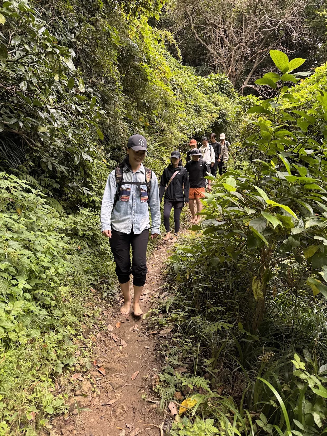 緑に囲まれた山道を一列になって裸足で歩く参加者